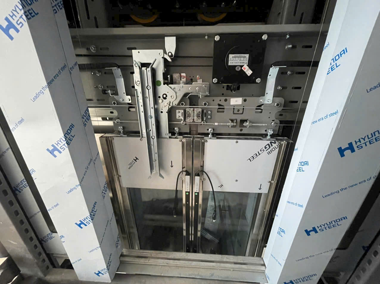 Cửa tầng thang máy Hyundai Steel đang lắp đặt với hệ thống cơ khí và cảm biến điều khiển